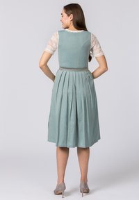 Hellgrünes Kleid mit einem plissierten Rock, strukturiertem Stoff und einem taillierten Oberteil. Es verfügt über einen kurzärmeligen Überwurf aus Spitze und einem passenden Gurt.