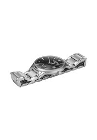 Reloj de acero inoxidable con esfera negra, manecillas plateadas y función de fecha. Pulsera de metal pulido con eslabones ovalados y un cierre seguro.