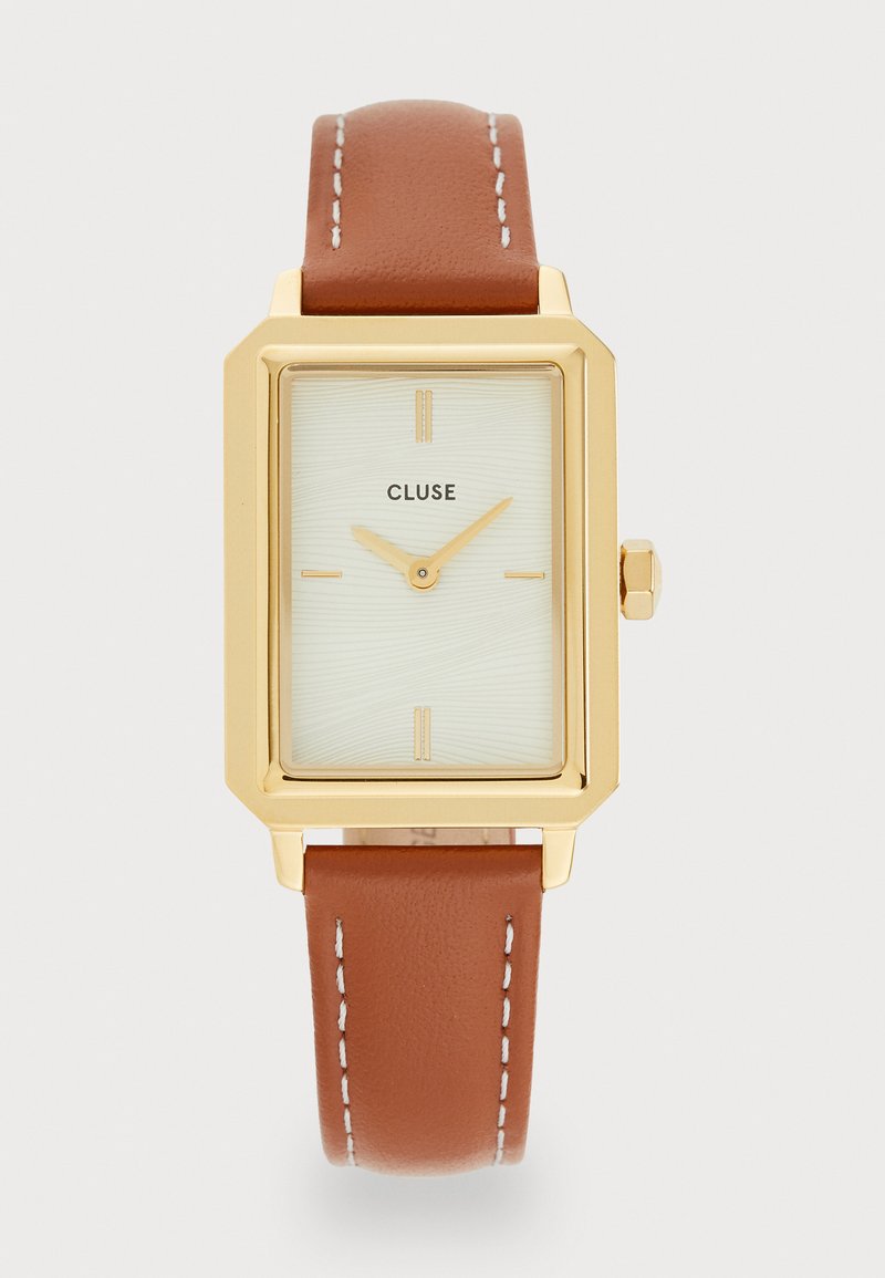 Montre rectangulaire dorée avec un cadran vert pâle texturé, des indicateurs d'heure minimalistes et un bracelet en cuir brun avec des coutures blanches.
