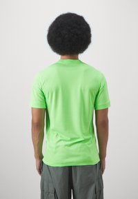 T-shirt a maniche corte in tessuto verde brillante, con colletto girocollo classico e superficie liscia; mostrato da dietro.