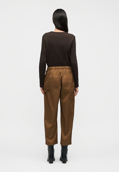 Καφέ πουκάμισο με μακριά μανίκια και στρογγυλή λαιμόκοψη, συνδυασμένο με καφέ cargo παντελόνι με ελαστική μέση, άνετη εφαρμογή, πλαϊνές τσέπες και ομαλή υφή.