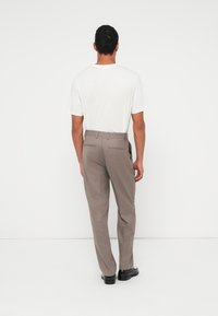 Γκρι παντελόνι προσαρμοσμένης ραφής με ομαλή υφή, με λεπτή κοπή, θηλιές για ζώνη και δύο πίσω τσέπες, συνδυασμένο με λευκό μπλουζάκι.