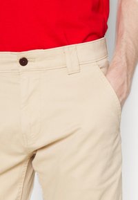 Beige katoenen broek met zijzakken, een gladde textuur en een bruine knop bij de tailleband. Ontworpen voor casual draag.