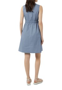 Ärmeloses, hellblaues Kleid mit elastischem Bund und ausgestellt Rock. Kombiniert mit weißen Sandalen mit Riemchen, aus glattem Stoff und knielangem Design.