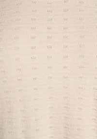 Textil de punto en crema con un patrón texturizado de pequeños puntos en relieve y franjas horizontales, creando un efecto sutil y en capas.