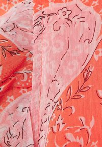 Tejido con estampado floral en tonos coral y rosa, que presenta intrincados dibujos de flores y formas orgánicas. Textura suave y ligera.