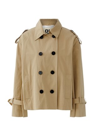 Beige cropped trench coat with double-breasted black buttons, wide collar, shoulder straps, front pockets, and adjustable sleeve straps.