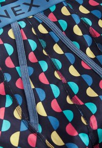 Culottes pour hommes en tissu bleu marine avec un motif à pois multicolores. Comprend une ceinture douce et des coutures visibles pour plus de détails.