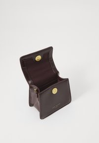 Mörk burgunderläderplånbok med en glänsande yta, som har ett enda guldknäppe och en öppen insida med mjukt tygfoder.
