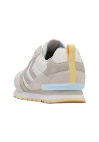 Jasnoszare sneakersy z zamszu i siateczki z żółtą wkładką na pięcie, niebieskimi akcentami, trzema białymi paskami po bokach oraz teksturowaną gumową podeszwą.