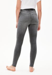 Vaqueros skinny de mezclilla gris con cintura alta, presentan bolsillos traseros y detalles de costura mínimos. Tejido texturizado y elástico para mayor comodidad.