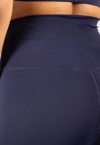 Granatowe sportowe szorty o wysokim stanie, charakteryzujące się gładką teksturą, płaskimi szwami i eleganckim designem, idealne do aktywności fizycznej.