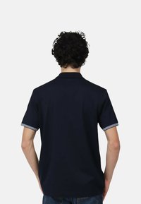Polo shirt navy con un colore solido, maniche corte e accenti a righe ai polsini. Presenta un colletto classico e un design slim fit.