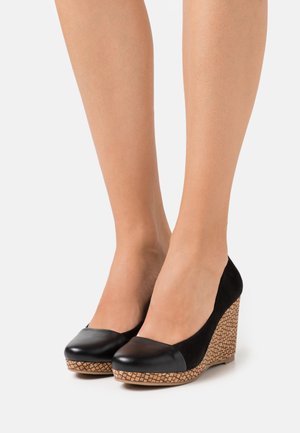 Chaussures à talons noirs avec un embout en cuir lisse, un dessus en daim et un talon à texture tissée, alliant hauteur et stabilité.