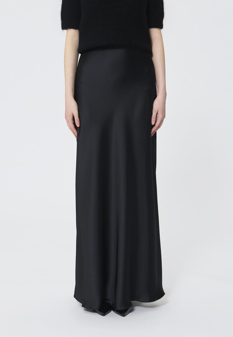 Zwarte satijnen maxi rok met een gladde textuur, strak ontwerp en een vloeiende silhouette, gecombineerd met een aansluitende zwarte trui.