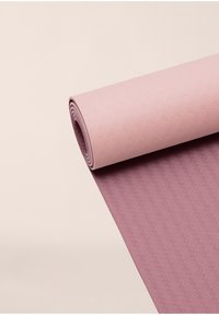 Tapis de yoga rose avec un motif de feuilles texturé sur le dessus et un design en chevrons en dessous, partiellement enroulé pour afficher les deux côtés.