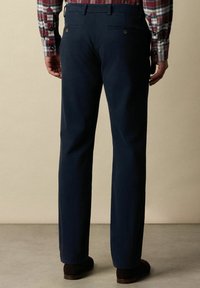Tmavě modré kalhoty vyrobené z hladké tkaniny, s dvěma zadními kapsami na knoflíky, úzkým střihem a rovnými nohavicemi.