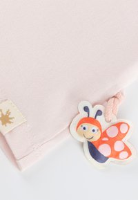 Pink cotton fabric with a smooth texture, featuring a looped tag of a smiling butterfly with an orange and blue design.