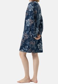 Abito a fiori in blu navy, realizzato in tessuto morbido. Presenta maniche lunghe e una vestibilità rilassata, con diverse tonalità di fiori azzurri e rosa.