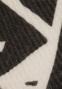 Tessuto testurizzato con un motivo geometrico in bianco e nero e sottili accenti metallici. Superficie liscia con un design diagonale.