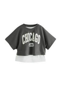 Grå kortærmet t-shirt med stort hvidt "CHICAGO" tekst og et mindre "USA" logo, lagdelt med en hvid kant i bunden. Korte ærmer.
