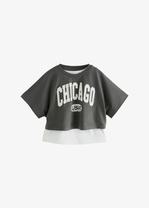 tricou gri scurt cu text mare alb "CHICAGO" și un logo mai mic "USA", stratificat cu o margine albă la baza. Mâneci scurte.