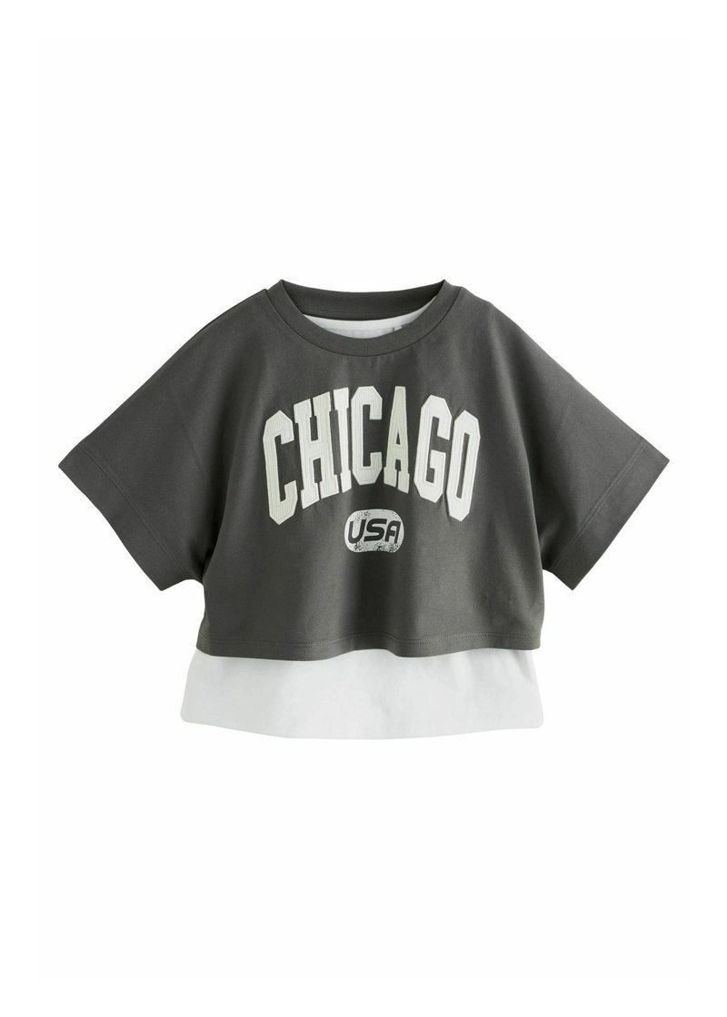 Grå kortærmet t-shirt med stort hvidt "CHICAGO" tekst og et mindre "USA" logo, lagdelt med en hvid kant i bunden. Korte ærmer.