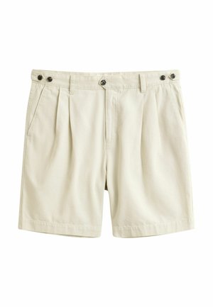 Shorts beige sur mesure avec plis sur le devant, poches latérales, fermetures à boutons à la taille et pattes latérales réglables sur fond blanc.