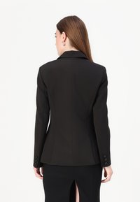 Svart skreddersydd blazer med spisse revers, strukturert passform, lange ermer og tre-knapps mansjetter. Glatt stoff med en slank silhuett.