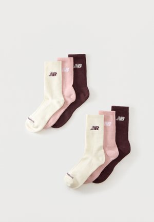 Deux ensembles de trois chaussettes New Balance montantes chacun, en crème, rose et marron foncé, étalées à plat sur fond blanc.