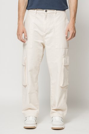 Pantalones cargo de algodón en beige claro, con bolsillos laterales y un diseño de pierna recta. Combinados con zapatillas blancas y una camisa azul marino.
