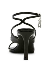 Schwarze High-Heel-Sandale mit glänzender Oberfläche, ausgestattet mit einem dünnen Knöchelriemen, offener Zehenpartie und einem silbernen Anhänger, der am Knöchelriemen hängt.