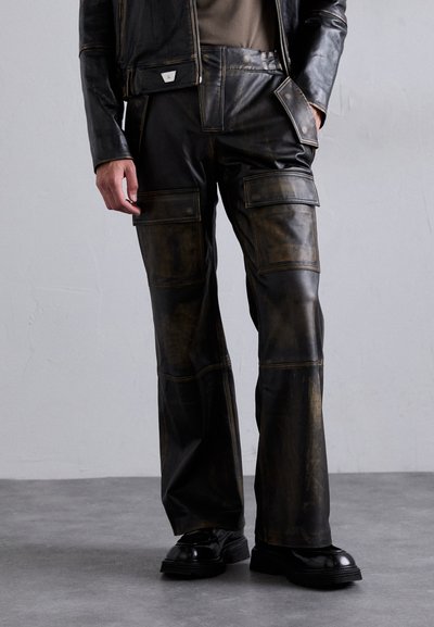 Pantalons en cuir noir avec une coupe large, plusieurs poches et une texture vieillie avec des accents brun doré.