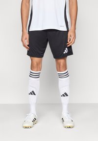 Crne sportske kratke hlače, bijele čarape s crnim prugama i bijele kopačke sa zlatnim detaljem. Lagan, tkanina koja upija vlagu, sportski dizajn.