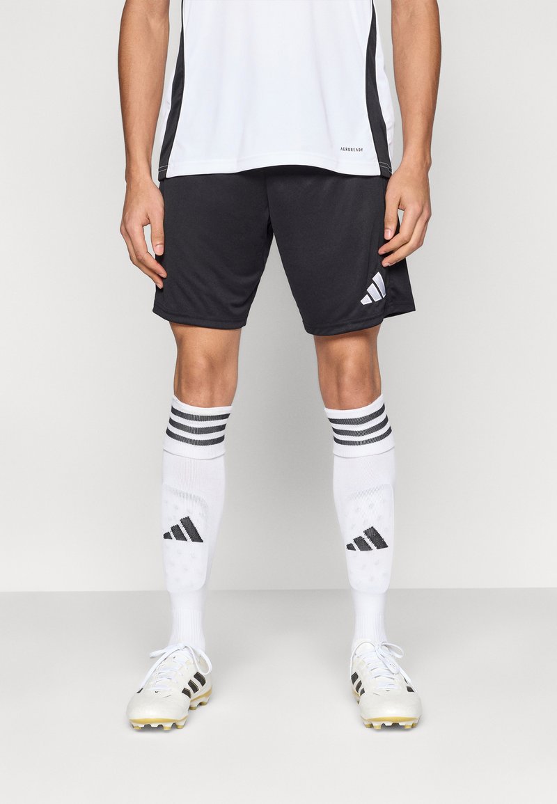 Crne sportske kratke hlače, bijele čarape s crnim prugama i bijele kopačke sa zlatnim detaljem. Lagan, tkanina koja upija vlagu, sportski dizajn.