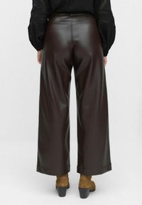 Pantalons larges en faux cuir brun foncé, présentant une texture lisse et une taille haute avec des détails de couture. Associés à des bottines brunes.