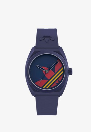 Modré hodinky na zápästie s červeným a žltým logom Adidas trefoil na ciferníku a zodpovedajúcim modrým silikónovým remienkom s reliéfom loga.