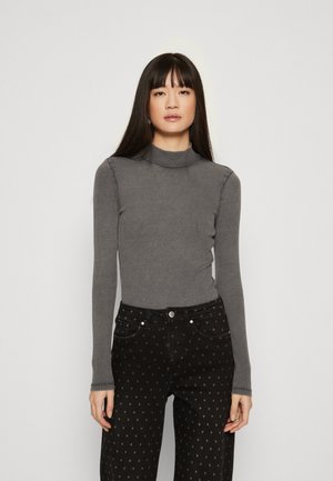 Γκρίζα ριγέ μπλούζα με μακρύ μανίκι και ψηλό γιακά, σε συνδυασμό με μαύρα τζιν ψηλής μέσης που έχουν σχέδιο με καρδιές.