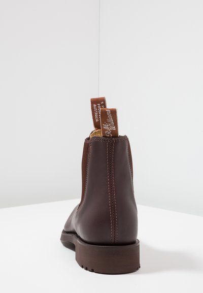 Bottines en cuir marron avec une texture lisse, des panneaux latéraux élastiques et des coutures contrastées. Comprend des languettes de tirage marron pour un enfilage facile.