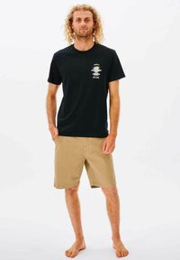 Zwarte katoenen T-shirt met een kleine kleurrijke graphic en tekst, gecombineerd met kaki shorts. Casual, lichtgewicht en geschikt voor warm weer.