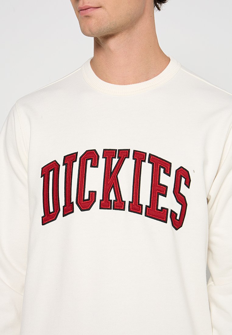 Felpa bianca con logo "DICKIES" rosso ricamato ad arco, con scollo rotondo e polsini a costine.