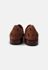Bruine suède schoenen met een ronde vorm, verfraaid met zwarte diamanten details, en een houten hak met een gestructureerde afwerking.