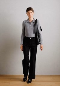 Polo gris de manga larga con canalé, pantalones de pierna ancha negros de talle alto y zapatos negros elegantes. Bolsa de hombro con una correa larga. Diseño simple y moderno.
