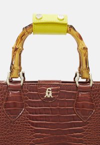 Sac à main en cuir marron à motif crocodile, avec une poignée en bambou, un accent en cuir jaune vif, des finitions dorées et un détail de logo.