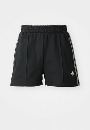 Črne športne hlače iz teksturirane tkanine, z elastičnim pasom, z zadrgo in tremi belimi črtami ob straneh, ki vsebujejo logo.