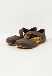 Scarpe in pelle marrone con punta arrotondata e piatta, design con cinturino incrociato e soletta in sughero imbottita. Cuciture evidenti lungo la suola.