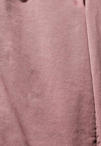 Tissu doux et texturé dans une couleur rose douce, avec une finition lisse et un éclat subtil, présentant de légères plis et une forme plate.