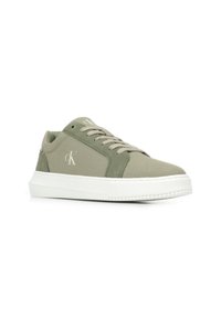 Groene canvas sneakers met een witte rubberen zool, voorzien van een gevoerde kraag en tong, vetersluiting en logo-detail aan de zijkant.