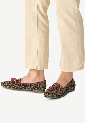 Zapatos planos de estampado de leopardo con detalles en rosa y borlas. Material de tela suave, punta redondeada y suela de perfil bajo. Llevados con pantalones de color claro.