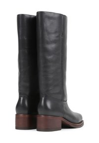Bottes en cuir noir montantes avec une texture lisse, une silhouette droite et un talon en bois empilé. Présente des détails de couture minimalistes.